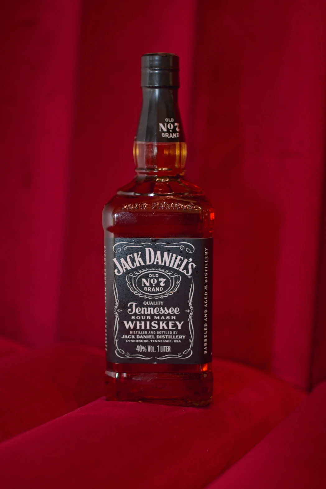 Butelka Jack'a Daniels'a na tle czerwonego weluru